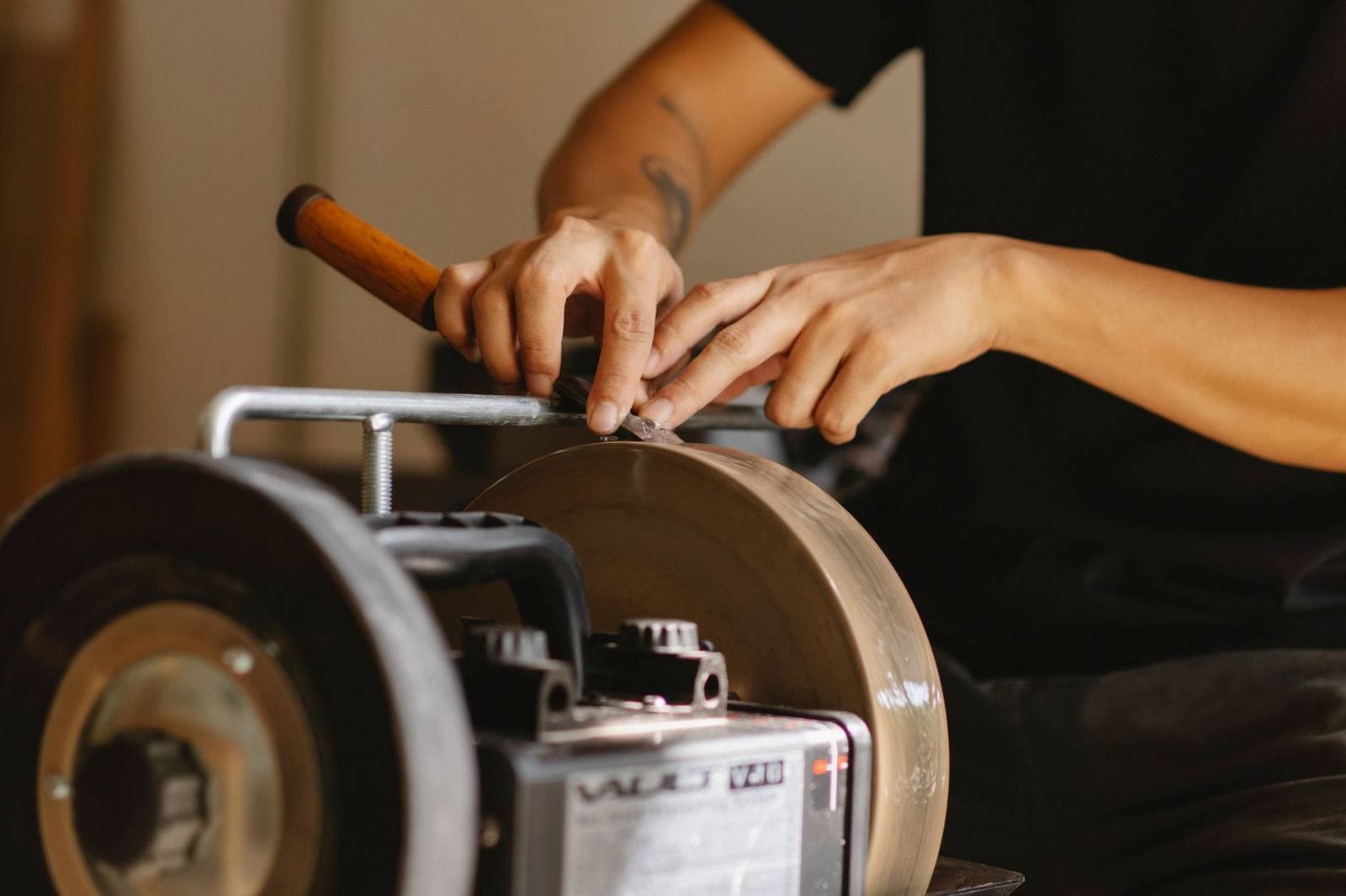 A craftsman grinding a chisel edge on a sharpening machine